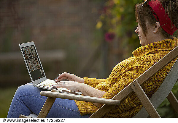 Frau mit Laptop im Liegestuhl
