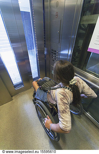 Frau mit Querschnittslähmung im Rollstuhl benutzt Aufzug  um Zugang zu trainieren