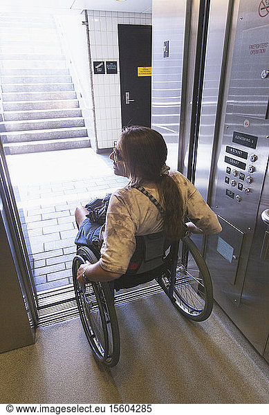 Frau mit Querschnittslähmung im Rollstuhl benutzt Aufzug  um Zugang zu trainieren