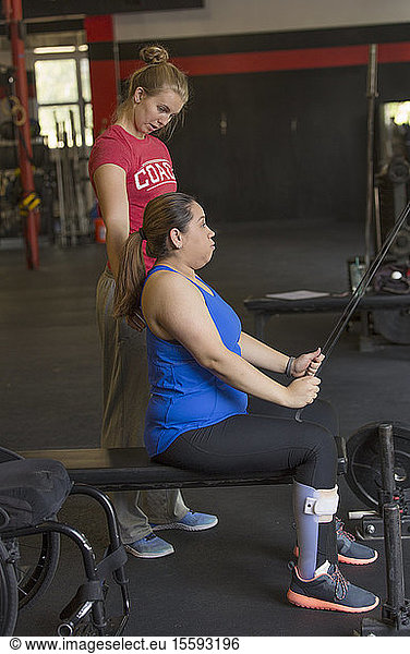 Frau mit Rückenmarksverletzung trainiert in einem Fitnessstudio mit einem Trainer