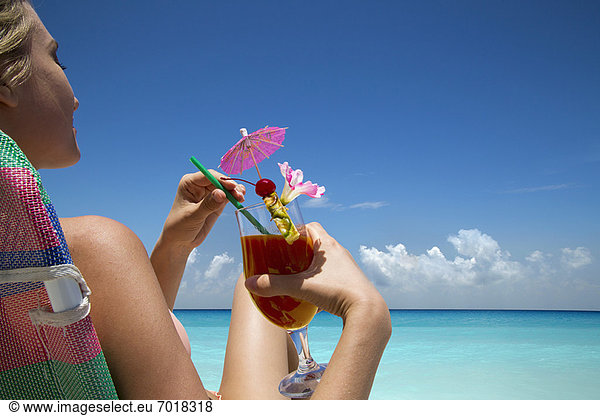 Frau mit tropischem Getränk am Strand