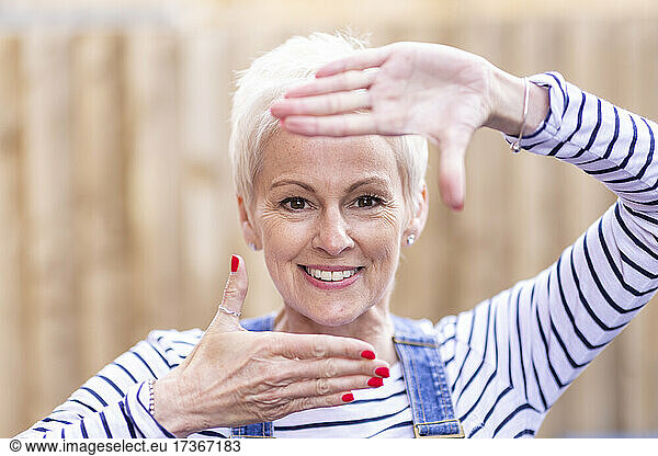 Frau mit weißem Haar macht Fingerrahmen
