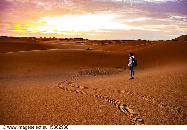 Frau mitten in der Wüste beim Sonnenaufgang