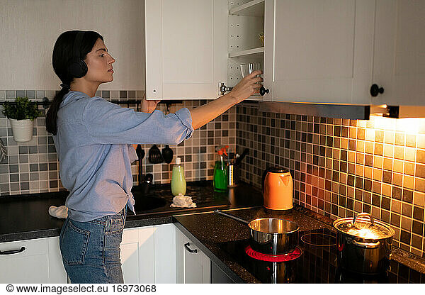 Frau räumt Geschirr in den Küchenschrank