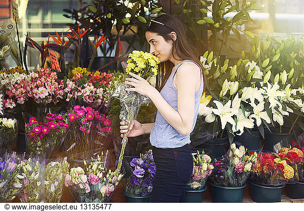 Frau riecht Blumen am Stand