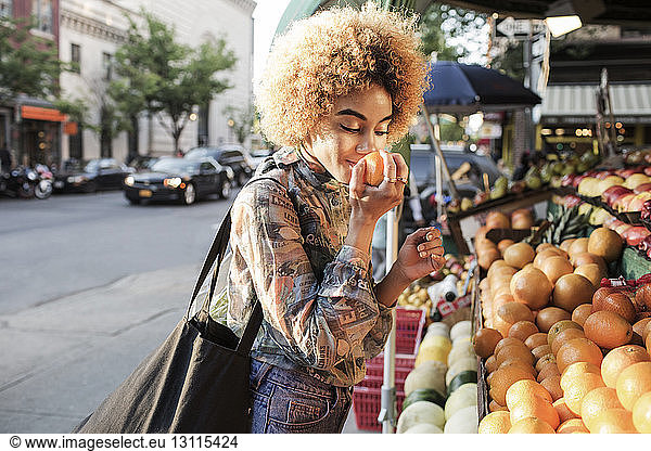 Frau riecht frische Orange am Marktstand