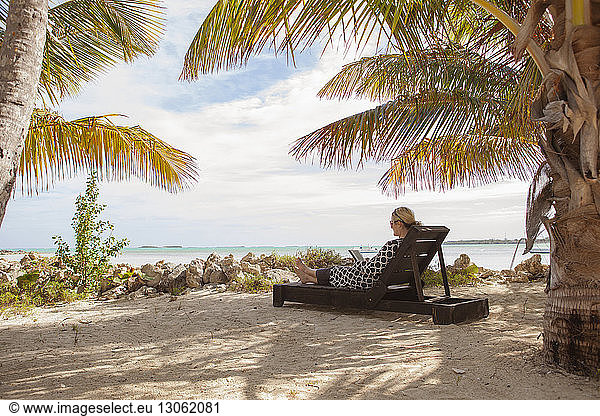 Frau ruht auf Liegestuhl am Strand