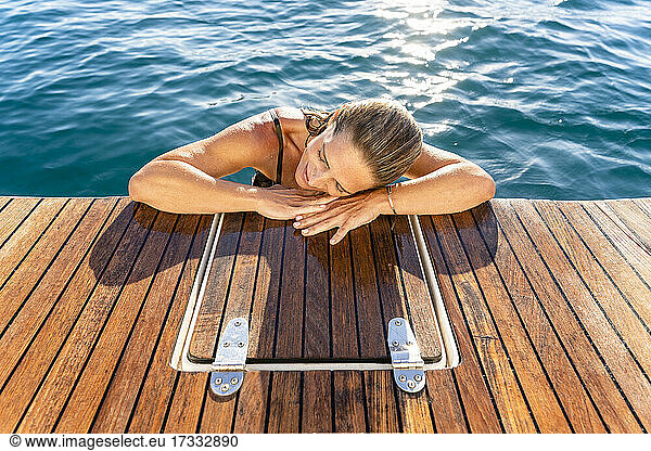 Frau ruht mit dem Kopf auf dem Deck eines Segelboots