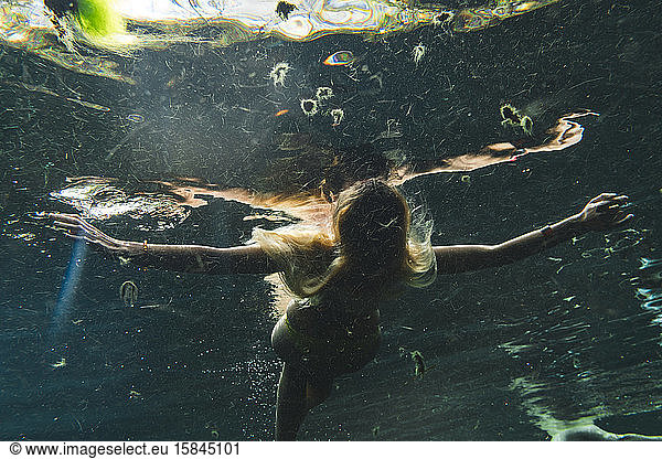 Frau schwimmt nahe der Wasseroberfläche und genießt Unterwasserbad