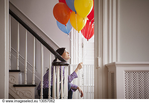 Frau sitzt auf der Treppe und hält Heliumballons