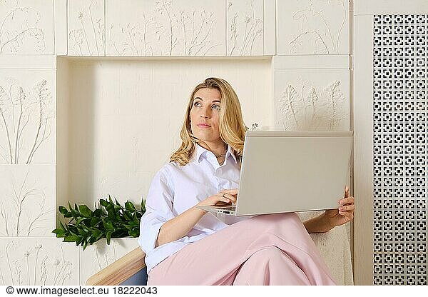 Frau sitzt im Sessel mit Notizbuch und sucht nach Informationen