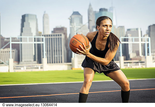 Frau spielt Basketball vor Gericht gegen Gebäude