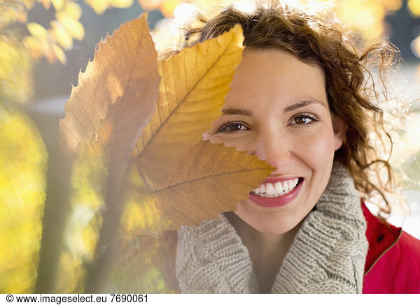 Frau spielt mit Herbstblättern