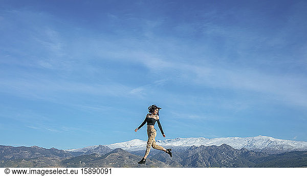 Frau springt mit Bergkette im Hintergrund