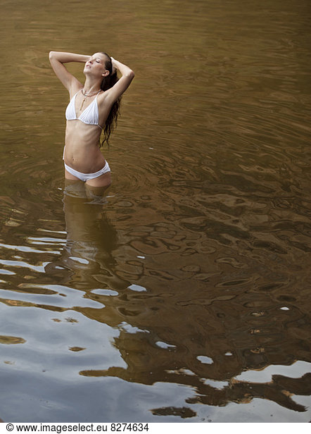 Frau stehend mit den Händen in den Haaren im Fluss