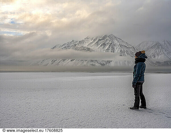 Frau steht am gefrorenen Ufer des Kathleen Lake und blickt auf die stimmungsvolle Landschaft; Haines Junction  Yukon  Kanada