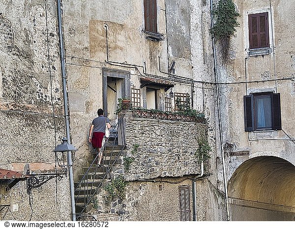 Frau steigt die Außentreppe eines mittelalterlichen Gebäudes hinauf  Bracciano  Region Latium  Italien.