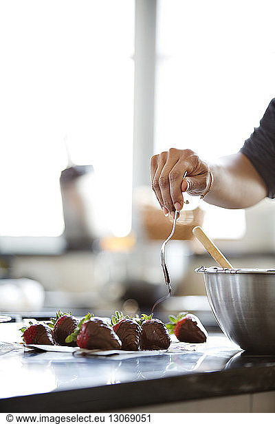 Frau streicht Schokolade auf Erdbeeren