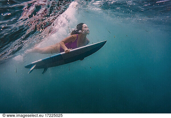 Frau surft auf Surfbrett unter Wasser