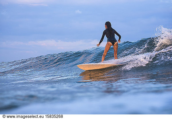 Frau surft bei Sonnenuntergang