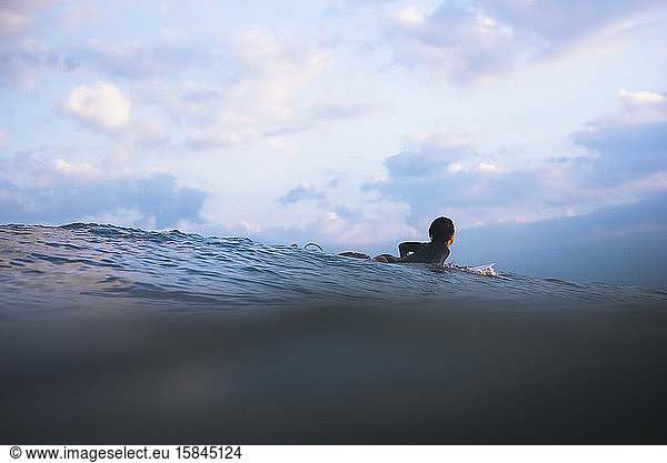 Frau surft bei Sonnenuntergang