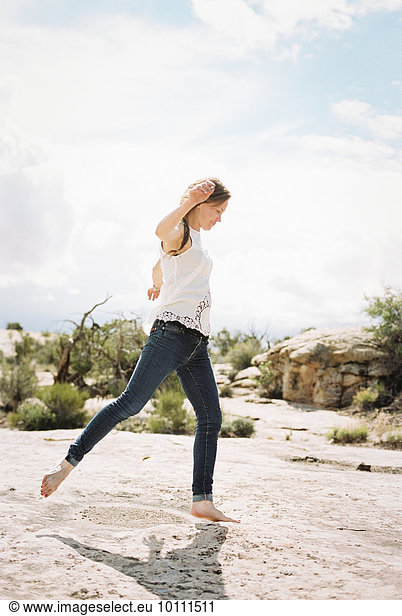 Frau tanzen Wüste barfüßig Jeans Kleidung