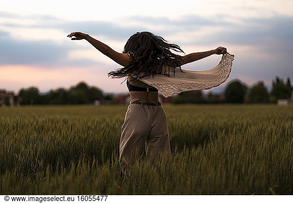 Frau tanzt auf einem Feld im Abendlicht