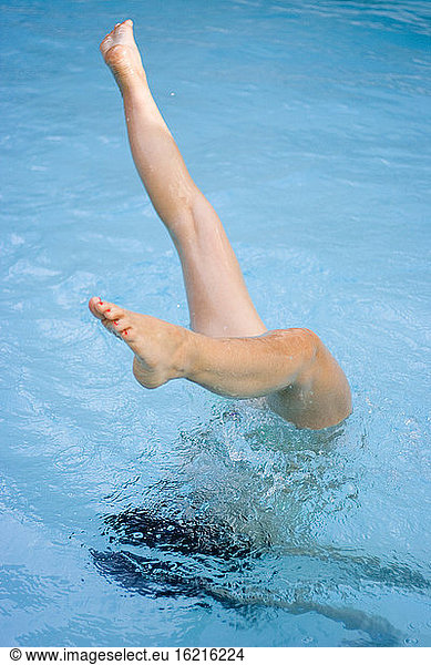 Frau taucht kopfüber in Schwimmbad