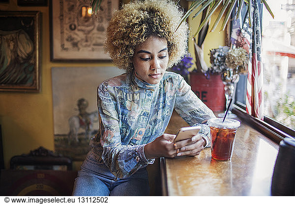Frau telefoniert bei einem Drink im Café