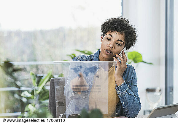 Frau telefoniert und benutzt transparentes Display zu Hause