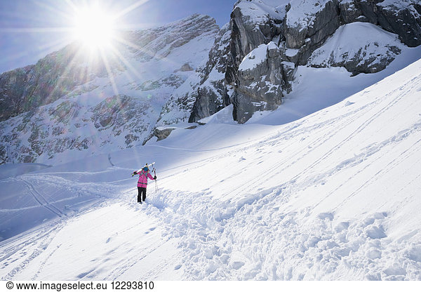 Frau trägt ihre Ski und geht im Schnee