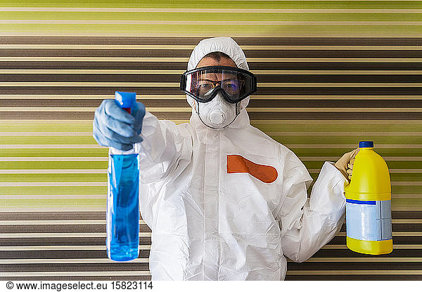 Frau trägt Schutzkleidung  desinfiziert ihr Haus