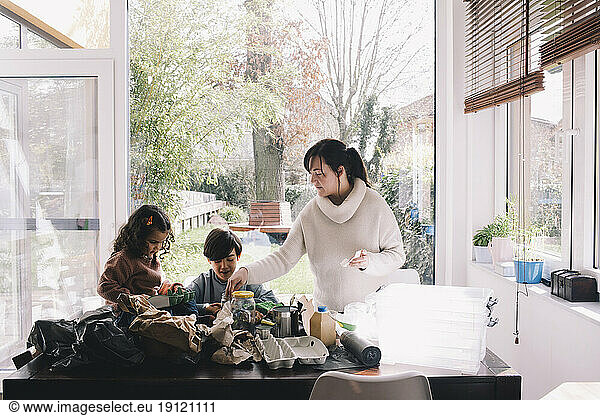 Frau trennt Abfall mit Sohn und Tochter zu Hause