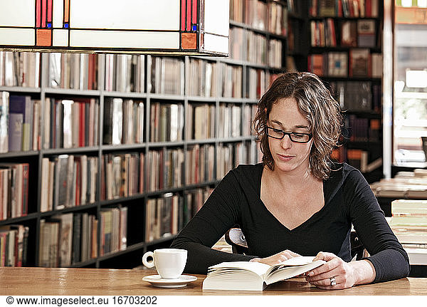 Frau trinkt Kaffee beim Lesen im Buchladen