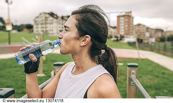 Frau trinkt Wasser beim Sport im Park