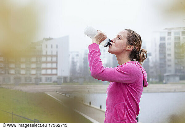 Frau trinkt Wasser in einem Park in der Stadt