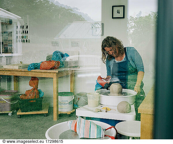 Frau trocknet Ton auf einer Töpferscheibe in ihrem Heimstudio im Vereinigten Königreich