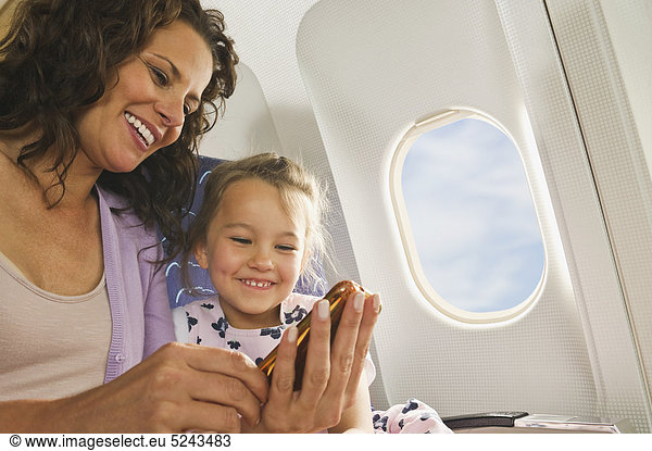 Frau und Mädchen mit Handy im Economy Class Airliner