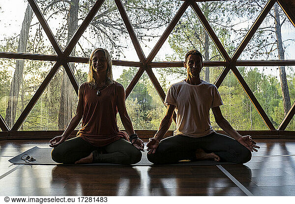 Frau und Mann üben Yoga am Fenster in einem Kurort