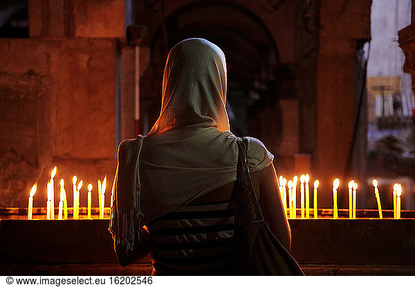 Frau vor einer Kerze in der Grabeskirche  Jerusalem  Israel