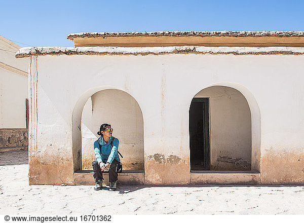 Frau wartet im Torbogen in einem kleinen Dorf in Purmamarca / Argentinien