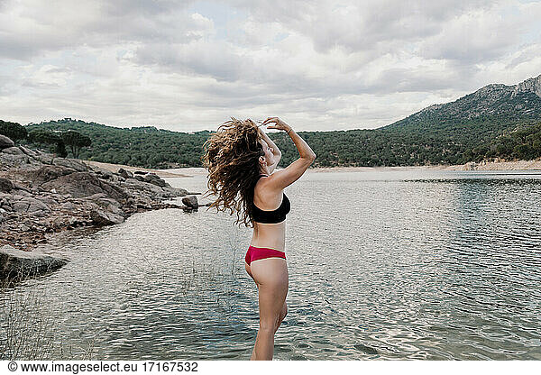 Frau wirft langes Haar  während sie am See steht