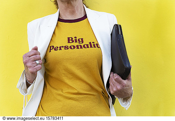 Frau zeigt gelbes T-Shirt mit großem Persönlichkeitsaufdruck