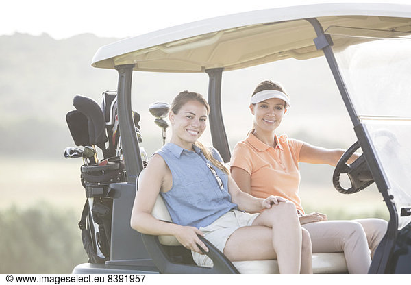 Frauen fahren Golfwagen auf dem Platz