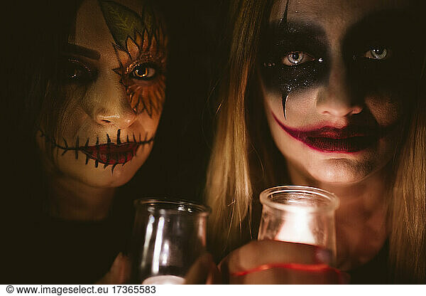 Frauen mit Halloween-Schminke halten beleuchtete Geräte