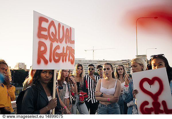 Frauen und Männer mit Plakaten  die für gleiche Rechte gegen den Himmel in der Stadt protestieren