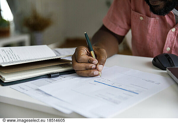 Freelancer calculating bills at desk in home