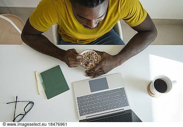 Freelancer having breakfast and working on laptop at home