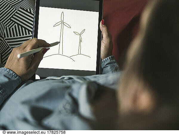 Freelancer making sketch of wind turbines on graphics tablet at home