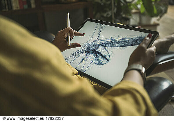 Freelancer pinching design of wind turbine on graphics tablet working at home